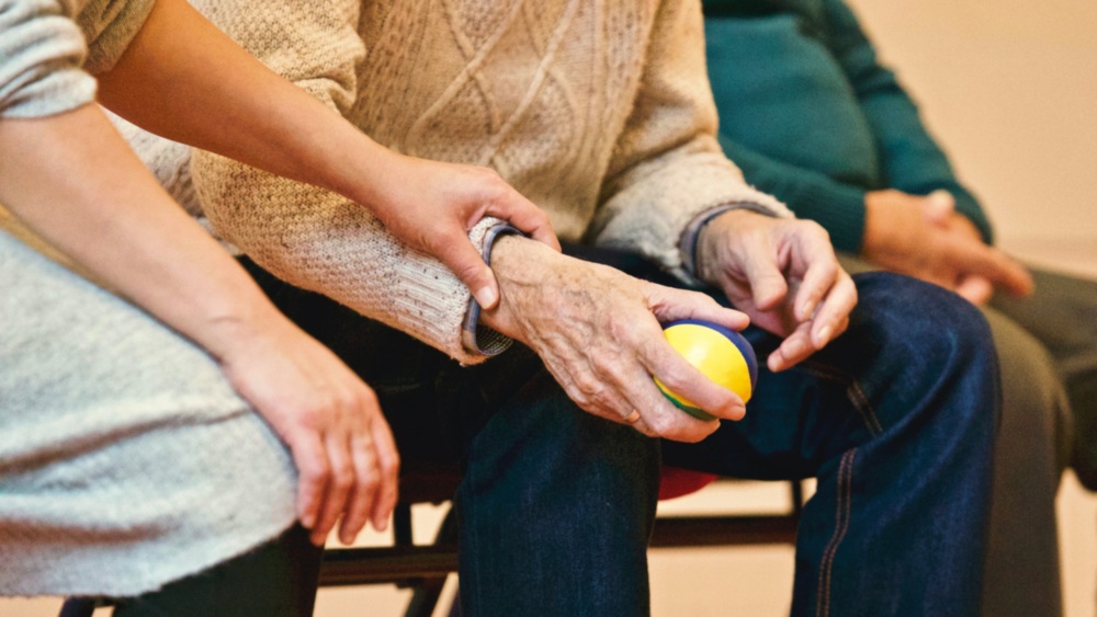 Older adult hands holding a therapy ball